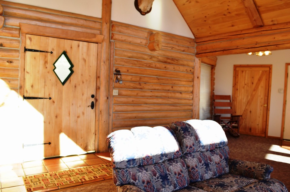great room open living area with interior exposed log and wood accents throughout.